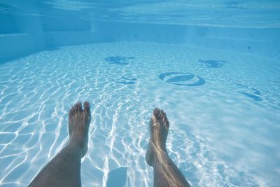 Low section of man swimming in pool