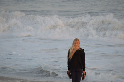 Rear view of woman standing at beach