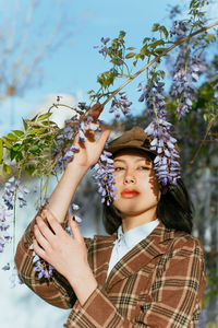 Portrait of young woman wearing hat holding leaves outdoors