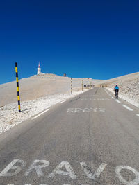 Road sign on land against clear blue sky