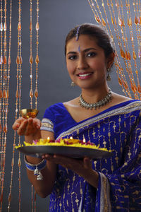 Portrait of beautiful indian woman in sari holding religious offerings during diwali