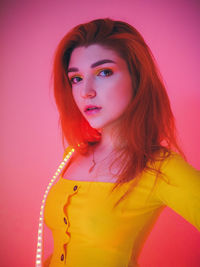 Portrait of beautiful young woman against pink background