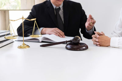 Midsection of male lawyer discussing with customer at desk