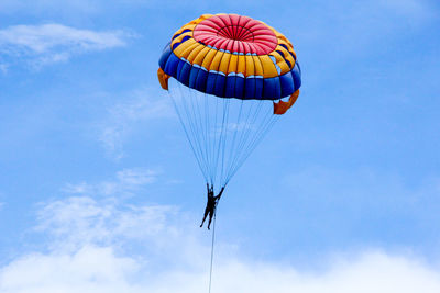 Low angle view of person paragliding against sky