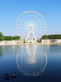 Ferris wheel in amusement park against clear blue sky