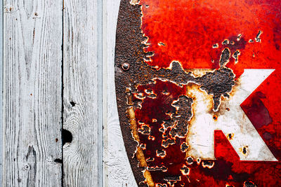 Close up of part of old rusty red sign on wooden wall