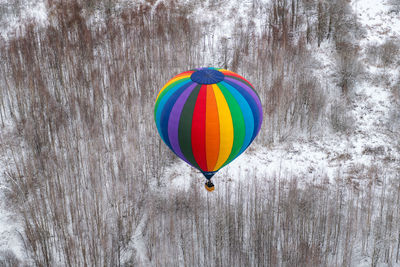Multi colored hot air balloon flying over trees