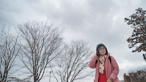 Portrait of young woman standing against sky