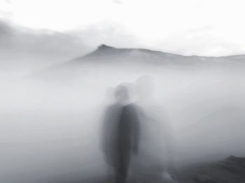 Rear view of people in foggy weather against sky