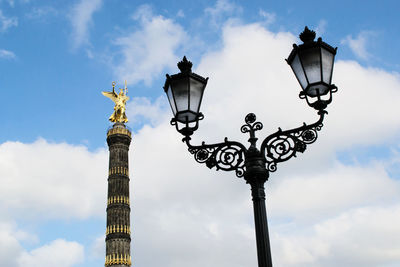 Low angle view of antique street light with berlin victory column against sky