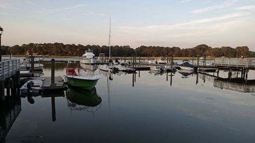 Boats moored at harbor against sky during sunset