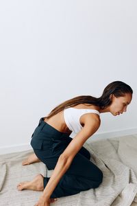 Portrait of young woman exercising against white background