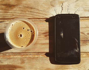 Directly above shot of coffee and smart phone on table during sunny day