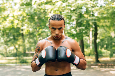 Portrait of shirtless man boxing on street