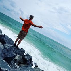 Full length of man jumping on beach against sky