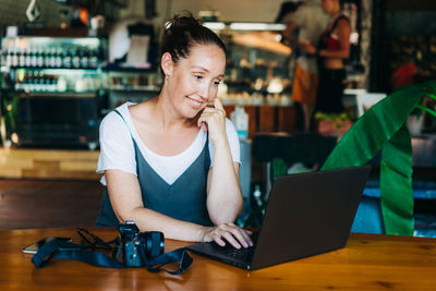 Portrait of woman using mobile phone while sitting on table