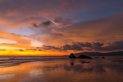 Scenic view of sea against dramatic sky during sunset