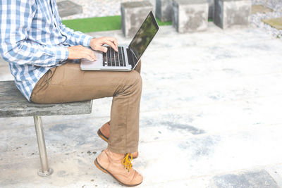 Low section of man using laptop while sitting in park
