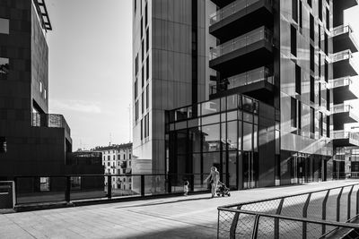 Rear view of mother with daughter on walkway against building in city