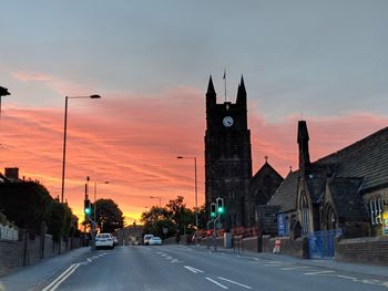 Road passing through city against sky during sunset