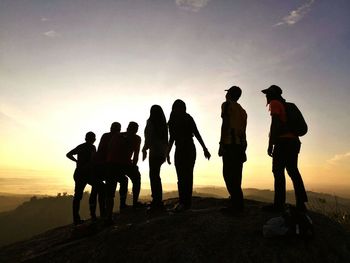 Silhouette people standing against sky during sunset