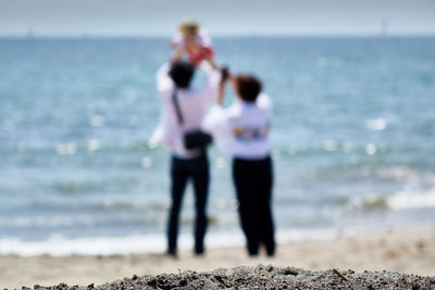 Defocused image of family standing on shore at beach