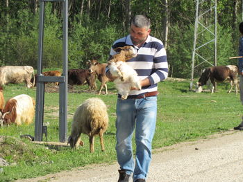 Man carrying lamb on dirt road