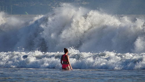 Full length of woman splashing water in sea