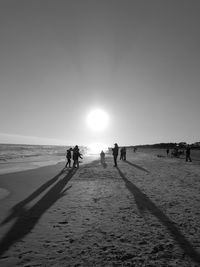 People walking on beach against clear sky