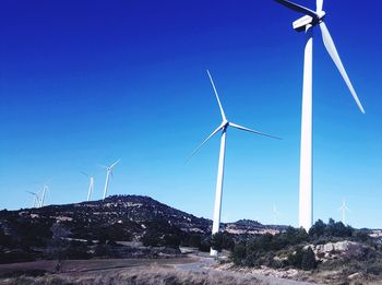 Low angle view of wind turbine against clear blue sky