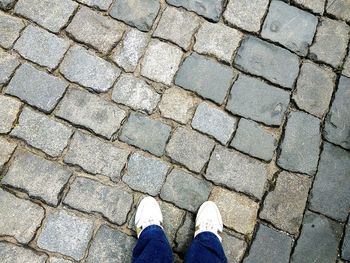 Low section of man standing on cobblestone