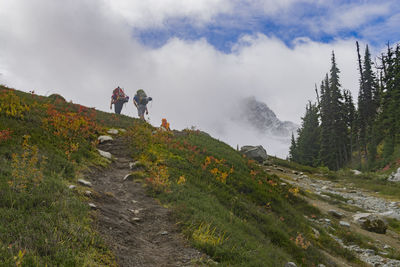 Low angle view of people walking on mountain against sky