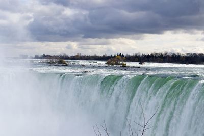 Scenic view of niagara falls against cloudy sky
