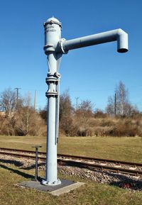 View of railroad tracks on field against clear blue sky