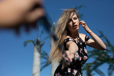 Young woman looking away against sky