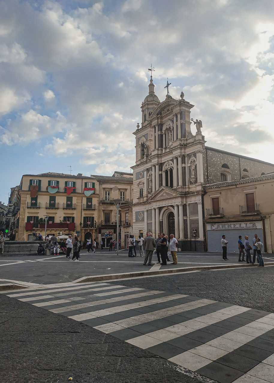 GROUP OF PEOPLE CROSSING ROAD AGAINST BUILDINGS