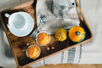 Morning coffee with pumpkin muffins on a wooden tray.