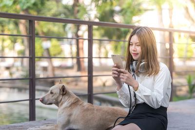 Young woman using smart phone while sitting outdoors