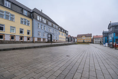 Empty street amidst buildings against sky