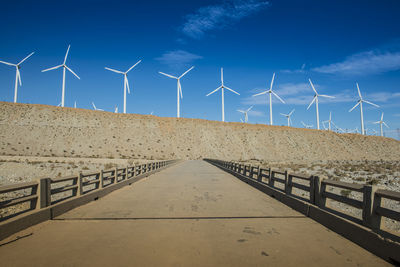 Wind turbines on land against blue sky