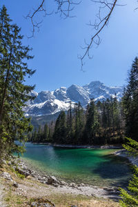 Scenic view of lake by snowcapped mountains against sky