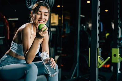 Portrait of young woman lifting dumbbell in gym