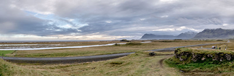 Scenic view of road by sea against sky