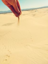 Cropped hand pouring sand at desert