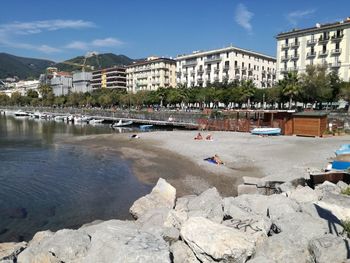 Boats in river by buildings against sky