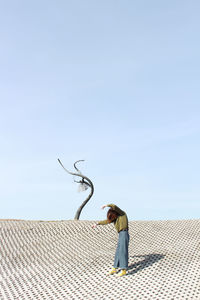 Side view of girl standing on tiled floor against sky