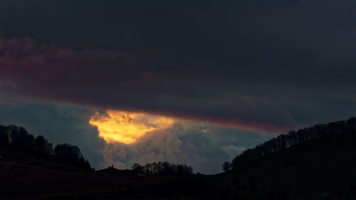 Scenic view of dramatic sky over silhouette landscape