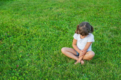 Side view of woman sitting on grassy field