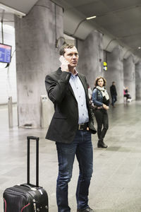 Businessman using mobile phone while standing at railway station