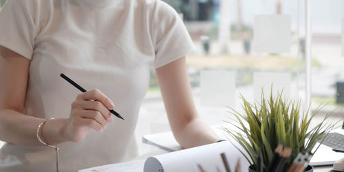 Midsection of woman holding umbrella on table